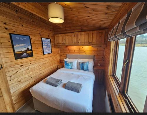 1 dormitorio en una cabaña de madera con 1 cama en Yare River Lodge Houseboat, en Stalham