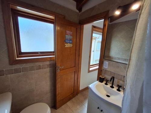 a bathroom with a sink and a toilet and a window at Joli Apartments - Studio 12 in San Martín de los Andes