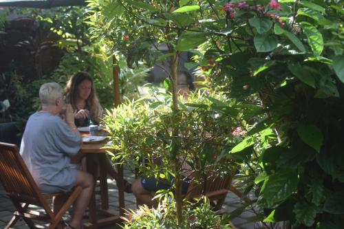 a man and woman sitting at a table in a garden at Werkudara Guest House in Ubud
