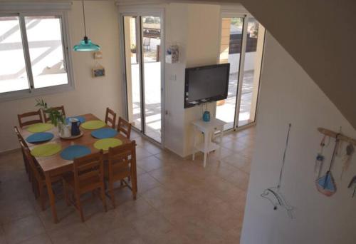 a dining room with a table and chairs and a television at Villa Calm 100m from the beach in Ayia Napa