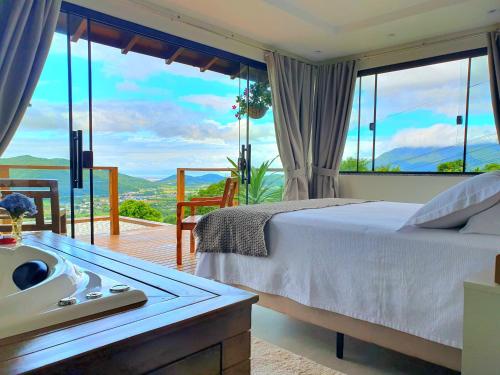 a bedroom with a bed and a balcony with a view at Recanto Pôr do Sol com banheira e lareira in Santo Amaro da Imperatriz