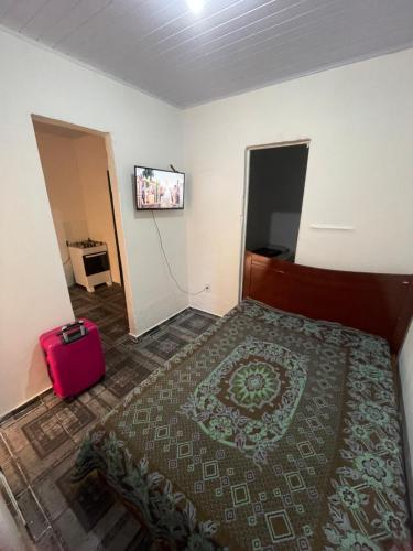 ein Schlafzimmer mit einem Bett und einem roten Koffer in der Unterkunft Casa avenida Sílvio Felício in Diamantina