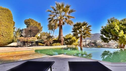 une piscine avec des palmiers et une ville dans l'établissement Palm & Sun, à Nice