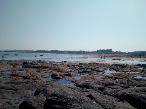 a beach with some rocks and the water at L'Anse de Landemer Montfarville in Montfarville