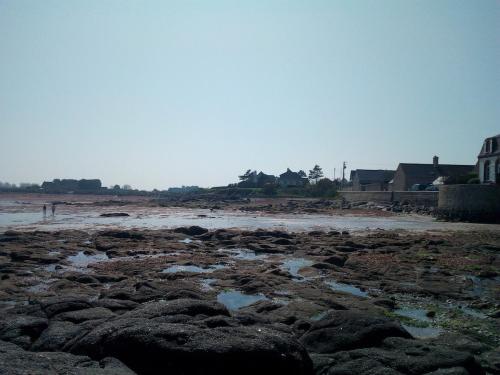 a beach with rocks and water and houses at L'Anse de Landemer Montfarville in Montfarville