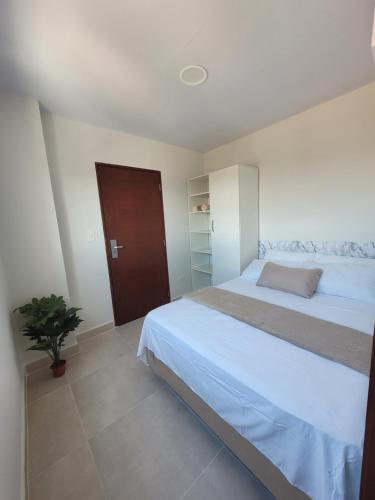 a bedroom with a white bed and a potted plant at Mirador del Cielo Apart-hotel Boutique in Santa Cruz de la Sierra