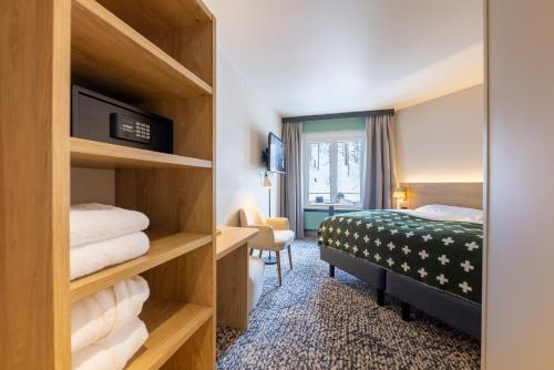 a hotel room with a bed and a chair at Hotel Schweizerhof Sils Maria, a Faern Collection Hotel in Sils Maria