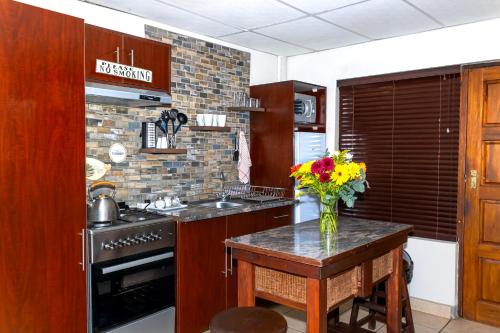 a kitchen with a table with a vase of flowers on it at A Cherry Lane Self Catering and B&B in Bloemfontein