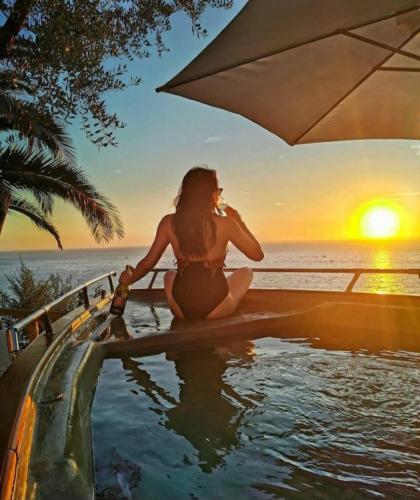 a woman in a bikini sitting in a pool watching the sunset at La Palombara B&B in Vico Equense