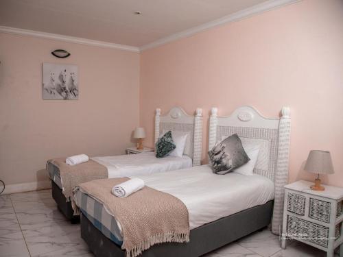 two beds in a room with two tables and a lamp at Heri guest house in Johannesburg