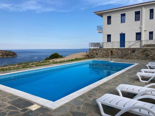 a swimming pool with chairs and a building at Archontiko Dagmar in Áyioi Apóstoloi