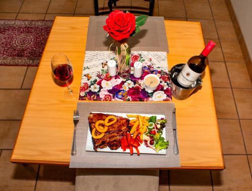 a table with two plates of food and a bottle of wine at A Cherry Lane Self Catering and B&B in Bloemfontein