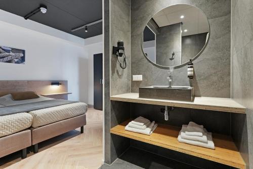 a bathroom with a bed and a sink and a mirror at Dock Hotel Stellendam in Stellendam
