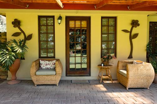 a yellow house with two chairs and a door at A Cherry Lane Self Catering and B&B in Bloemfontein
