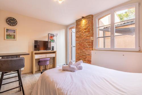 une chambre avec un lit, un bureau et une fenêtre dans l'établissement Le cocon Toulousain, à Toulouse