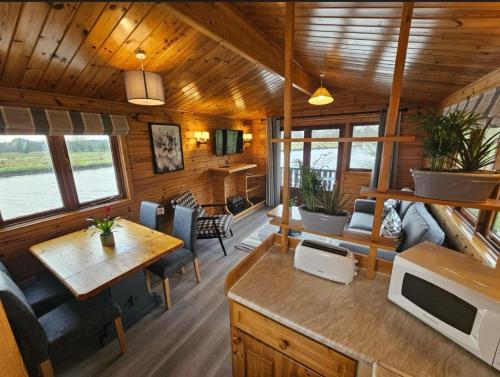 Cabaña con comedor y sala de estar en Hickling Broads Lodge Houseboat, en Stalham