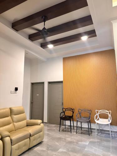 a waiting room with a couch and two chairs at Homestay Husna in Dungun