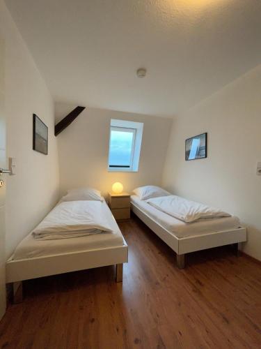 two twin beds in a room with a window at Ferienwohnung West in Fehmarn
