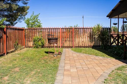 a backyard with a fence and a swing at A Cherry Lane Self Catering and B&B in Bloemfontein