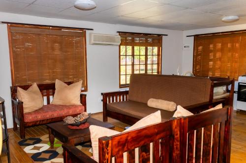 a living room with a couch and chairs and windows at A Cherry Lane Self Catering and B&B in Bloemfontein