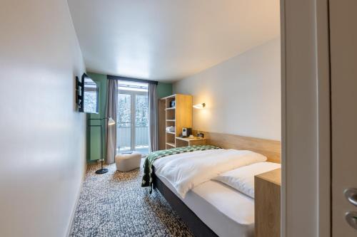 a hotel room with a bed and a window at Hotel Schweizerhof Sils Maria, a Faern Collection Hotel in Sils Maria