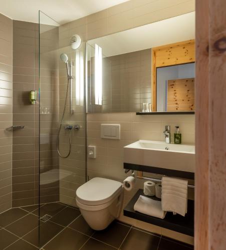 a bathroom with a toilet and a sink and a shower at Hotel Schweizerhof Sils Maria, a Faern Collection Hotel in Sils Maria