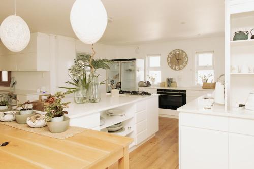 a white kitchen with a table and a clock at Thyme & Tide Beach Villa in Yzerfontein
