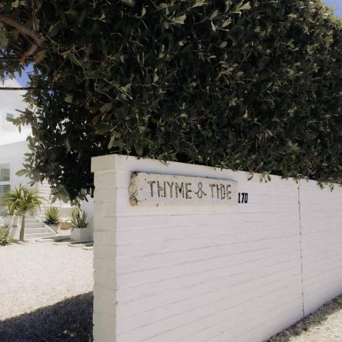a white wall with a sign that reads think and thema at Thyme & Tide Beach Villa in Yzerfontein