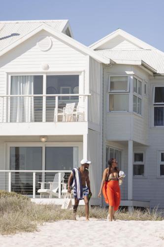 two people walking on the beach in front of a house at Thyme & Tide Beach Villa in Yzerfontein