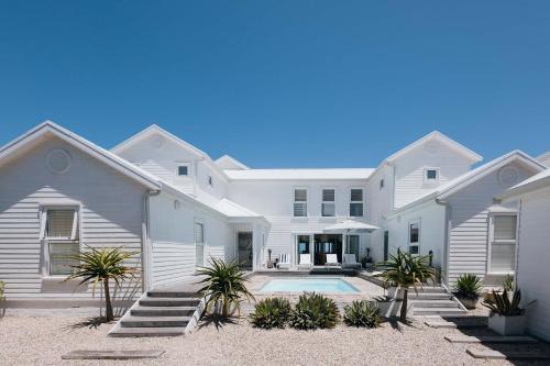 a large white house with a swimming pool at Thyme & Tide Beach Villa in Yzerfontein