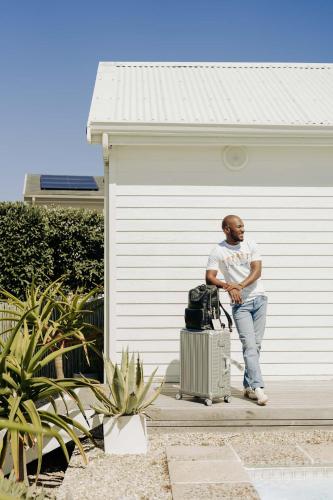 a man sitting next to a building with a suitcase at Thyme & Tide Beach Villa in Yzerfontein