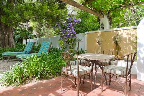 a patio with a table and chairs and flowers at Woodall Country House and Spa in Addo