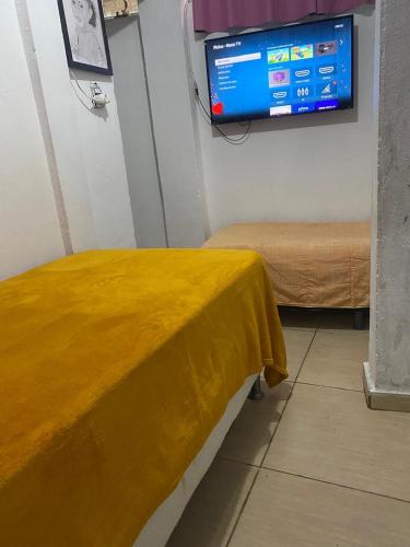 Cette chambre comprend un lit et une télévision murale. dans l'établissement Kitnet Diamantina, à Diamantina