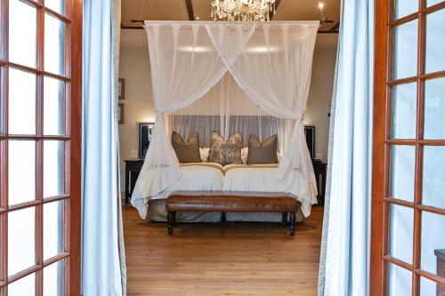 a bed with a canopy in a room with windows at Woodall Country House and Spa in Addo