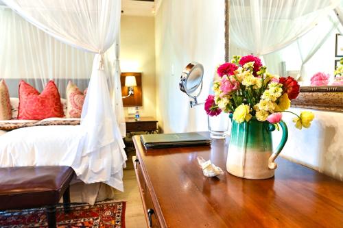 a bedroom with a vase of flowers on a table at Woodall Country House and Spa in Addo