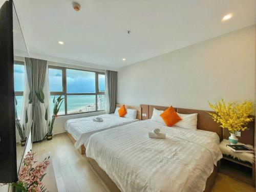 a bedroom with two beds and a large window at Apartment Galaxy The Song Vung Tau Homestay in Vung Tau