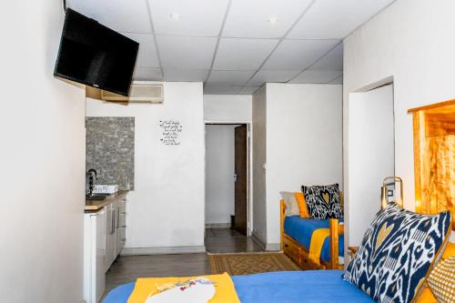a small room with a blue bed and a kitchen at A Cherry Lane Self Catering and B&B in Bloemfontein