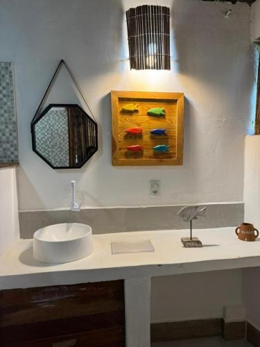 a bathroom with a sink and a painting on the wall at Igapeba Hospedaria em Moreré in Cairu