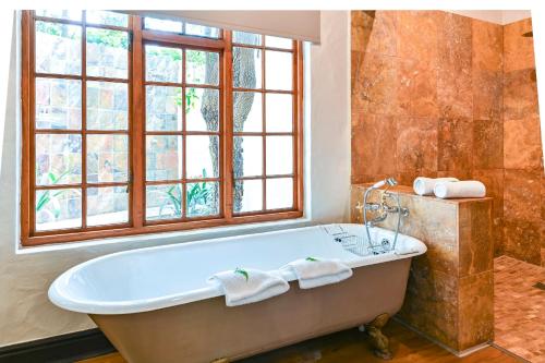 a bath tub in a bathroom with a window at Woodall Country House and Spa in Addo