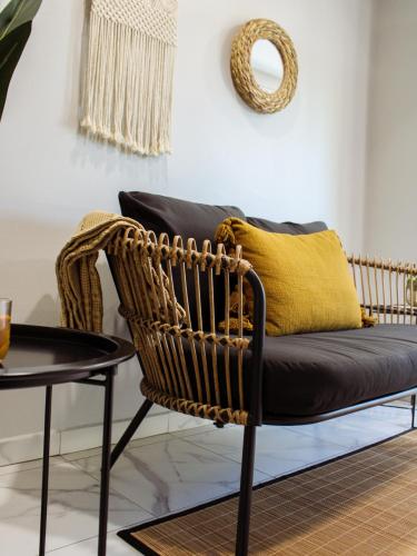 a wicker chair with a yellow pillow and a table at Eva Spa Resort Rooftop Pool 1br By Lucha in Savaneta