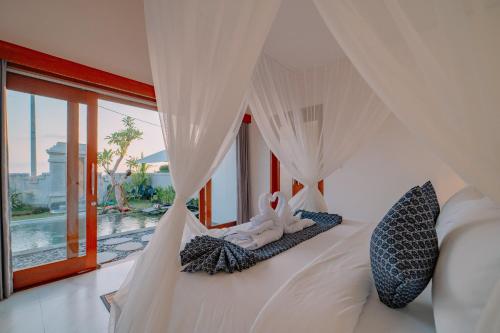 a bedroom with a white bed with a canopy at Arca Bali Private Pool Villa in Ubud