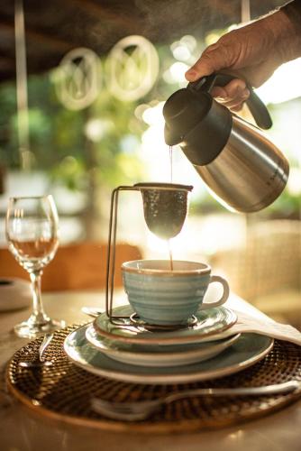 a person pouring coffee into a cup on a table at Pousada Morena in Fernando de Noronha