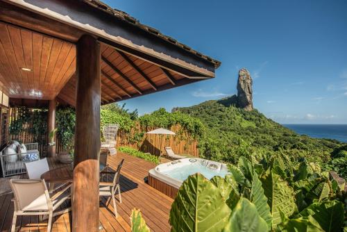 an outdoor deck with a hot tub and the ocean at Pousada Morena in Fernando de Noronha
