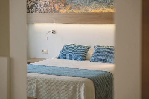 a bedroom with a bed with blue pillows at Aparthotel Novo Mar in Paguera