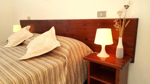 un letto con due cuscini e un tavolo con una lampada di Ferienhaus Casa Limone - Villaggio Galanu a Costa Paradiso