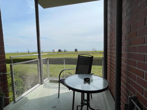 a table and chair on a balcony with a view of a field at Apartment 10 in Wilhelmshaven