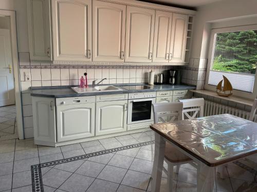 a kitchen with white cabinets and a table at Ferienhaus Osterende in Bordelum