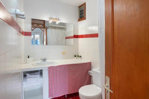 a bathroom with a sink and a toilet and a mirror at La Bayana Apartments - 3 in Puerto Naos