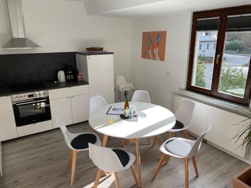 a white kitchen with a white table and chairs at Ferienhaus Loreleytraum, Wohnung Obergeschoss in Sankt Goarshausen