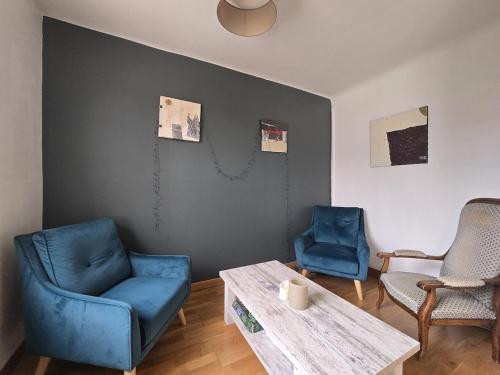 un salon avec deux chaises bleues et une table dans l'établissement la maison de caramel, au Mans